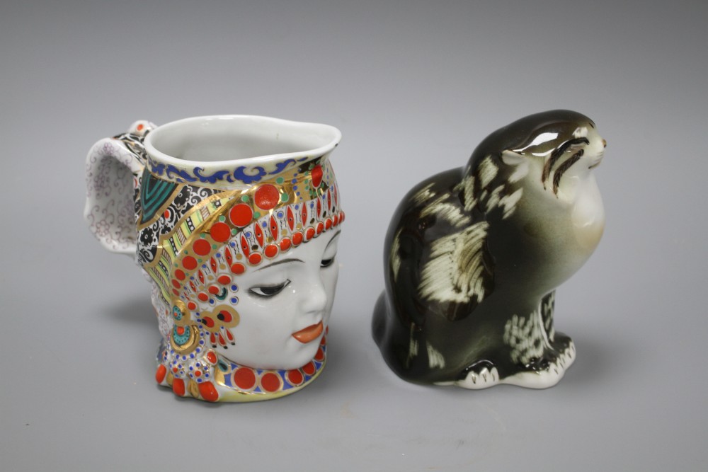 A Russian ceramic figure of a seated cat, height 15cm, and a character jug depicting a womans head with elaborate head-dress, height 1
